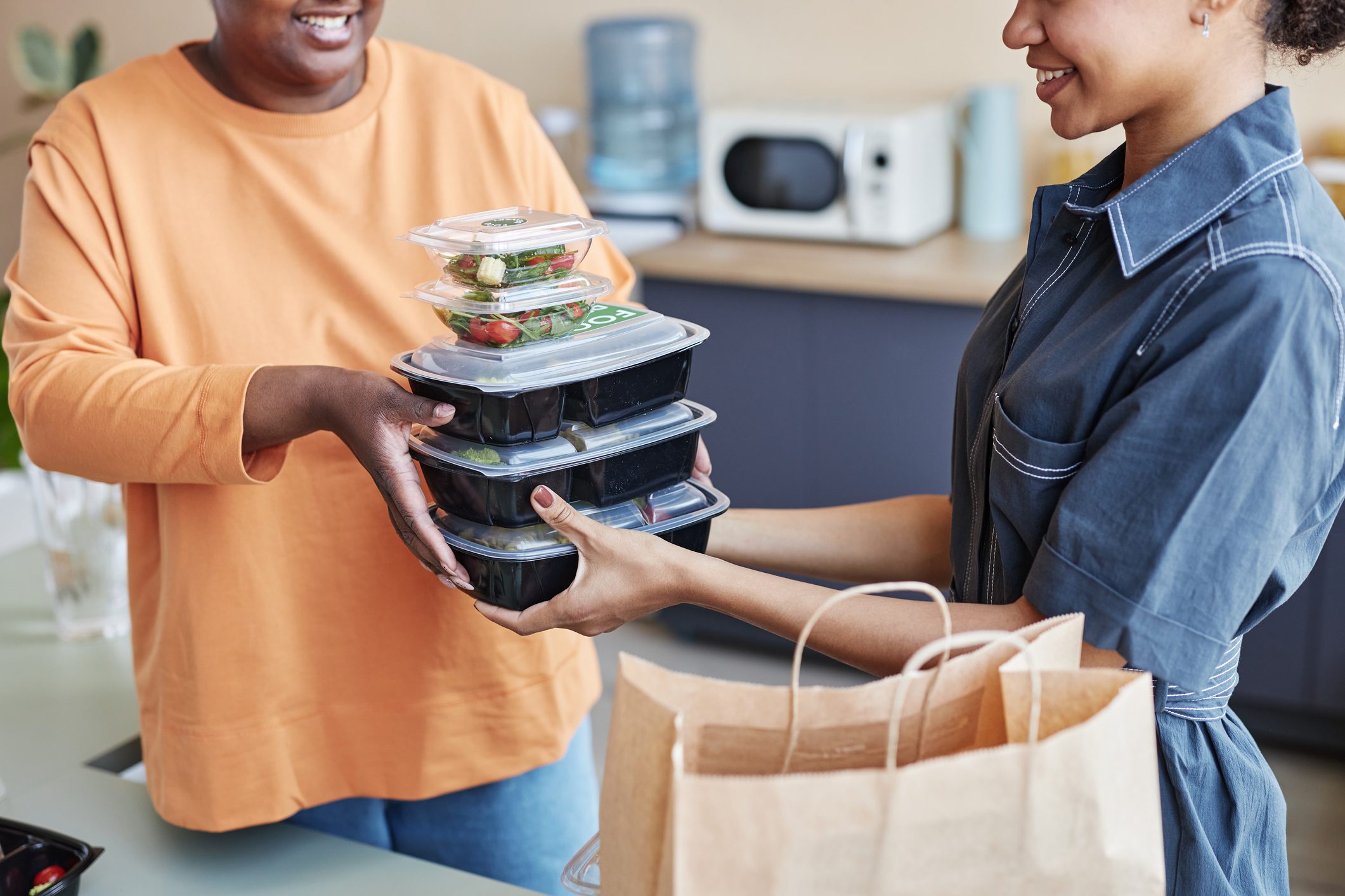 Cropped portrait of two African American women unpacking food delivery order at home